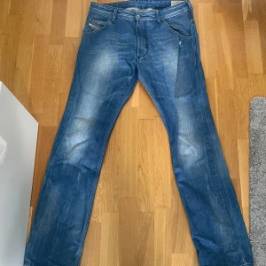 Blå Diesel Krooley jeans W30 L32 - Säljer ett par blå Diesel Krooley jeans med snygga slitningar och klassisk femficksdesign. Modellen har en rak passform och normal midja,.