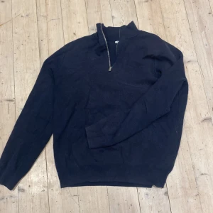 Mörkblå stickad tröja med half zip från Zara - Snygg mörkblå stickad tröja från Zara med half zip i halsen. Tröjan har långärmade ribbade muddar och en stilren, enkel design som passar perfekt till jeans eller chinos. Materialet är mjukt och håller dig varm under kyliga dagar.