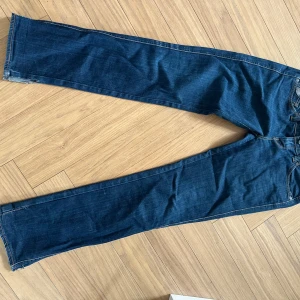 Mörkblå lågmidjade jeansbyxor - Säljer ett par mörkblå jeansbyxor i lite tajtare bootcut. Jeansen har fem fickor, kontrastsömmar och är tillverkade i slitstarkt denim. Perfekta för dig som gillar en tidlös look med lite vidare ben nertill. Märkesjeans från lois, säljer lite billigare då jag har klippt upp dom (syns på bild). Skulle säga att dom passar storlek xs-s