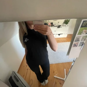 Svart t-shirt från Calvin Klein Jeans - Svart t-shirt från Calvin Klein Jeans med diskret CK-logga på bröstet. Slim fit-modell som sitter snyggt och har klassisk rund hals. Tillverkad i mjuk bomull som känns skön mot huden. Perfekt för dig som gillar stilrena och enkla plagg.