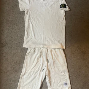 Vita shorts och t-thirt från Stone Island S men sitter som M - Snygga vita shorts från Stone Island med elastisk midja och snörning. Klassisk patch med logga på benet och stilren design. Perfekta för sommardagar när du vill ha en clean och avslappnad look.