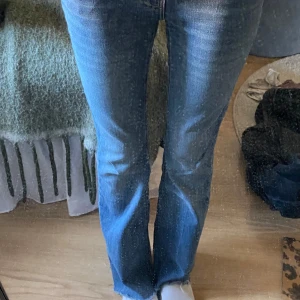 Blå bootcut jeans från Perfect Jeans - Säljer ett par klassiska blå bootcut jeans från Perfect Jeans i storlek 32. Jeansen har en snygg mellanblå tvätt, fem fickor och normal passform. Tillverkade i mjukt denimtyg med lätt stretch för extra komfort. Perfekta för dig som gillar en tidlös look.
