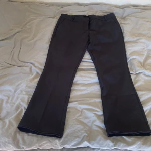 Svarta bootcut kostymbyxor - Snygga svarta kostymbyxor med bootcut-snitt och klassiska pressveck. Byxorna har hällor för bälte och stängs med dragkedja . Perfekta för en clean och stilren look. Materialet känns mjukt och följsamt. Har sytt upp 3 cm. De passar perfekt för mig och jag är 160.