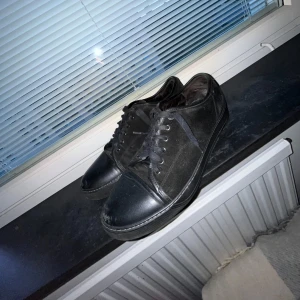 Svarta lanvin  - Stilrena svarta lanvins med snörning och platt sula. Ovandelen är i textil och tåpartiet samt detaljer i skinnimitation. Perfekta för dig som gillar en clean och enkel look till vardags. Sulan har byts.