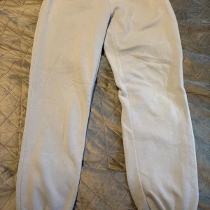 Ljusgrå/blå mjukisbyxor med resår - Säljer ett par ljusgrå mjukisbyxor med resår vid bensluten. Perfekta för chill dagar eller när du vill vara extra bekväm. Byxorna har en enkel design och är gjorda i mjukt material som känns skönt mot huden.