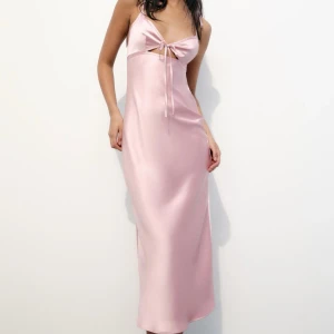 Rosa långklänning från Zara - Elegant rosa långklänning i satin med en dekorativ rosett framtill. Perfekt för en festlig kväll. Köpt på Zara förra året endast använd 1 gång.