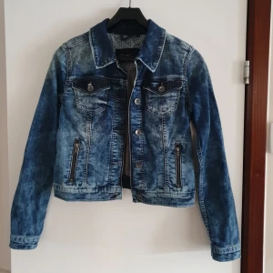Blå jeansjacka från BlendShe - Snygg blå jeansjacka från BlendShe med klassisk krage och knappar framtill. Jackan har två bröstfickor med knapp och två sidofickor med dragkedja. Perfekt för en avslappnad stil. Storlek 36/S. Helt oanvänd, men jag hann klippa bort lappen. Bakstycke 46 cm.