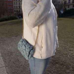 Blå quiltad axelväska med kedja - Snygg blå axelväska med quiltad design och guldfärgad kedja. Väskan har en unik textur och en praktisk storlek för dina nödvändigheter.