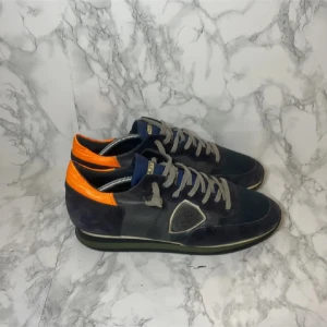 Phillippe Model Skor  - Snygga sneakers i blå mocka med detaljer i orange och grått. Skorna har en klassisk snörning och en bekväm sula. Perfekta för en stilren look med en färgglad twist. Storlek 41-42