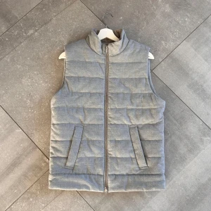 Grå quiltad dunväst - Snygg grå quiltad dunväst från Dressman med dragkedja och hög krage.  Endast använd fåtal gånger så skick: (8,8/10) Stolek: (S)