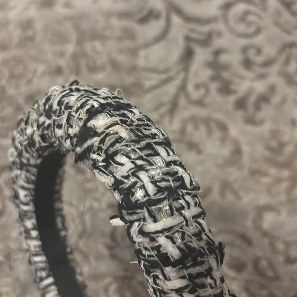 Snyggt diadem i svart och vitt med ett flätat mönster. Perfekt för att ge en stilfull touch till din outfit. Diademet har en texturerad yta som ger det en unik look.. Asusteet.