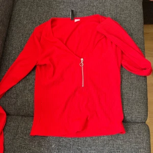 Röd ribbad tröja med dragkedja - Snygg röd ribbad tröja med v-ringning och dragkedja framtill. 