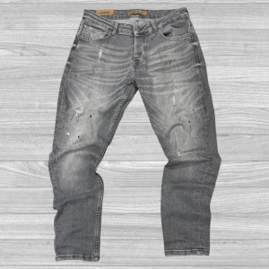 Indigolab jeans - Snygga grå jeans från Indigolab med en cool, sliten look och färgstänk. De har en klassisk femficksdesign och knappgylf. Perfekta för en avslappnad stil.