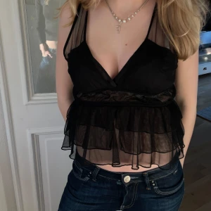 svart fest topp med volanger - Snygg svart topp med volanger och djup v-ringning, i fint skick! Perfekt till fest💥
