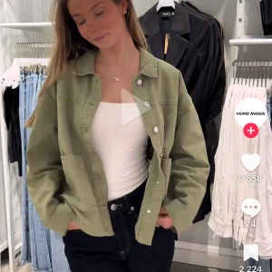 Grön jacka från Vero Moda - Snygg grön jacka från Vero Moda med knappar framtill. Jackan har en avslappnad passform och långa ärmar. Perfekt för en stilren look. Storlek L, säljer då den ej passade mig, passar även S/M om man vill ha den oversized, personen på bilden bär M
