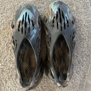 Yeezy foam rnr MX Cinder - Nästan helt oanvända foam rnr, köpta från Sneaker Cuisine.                                                     Har kvitto.                                                                            Låda tillkommer.                                                               Storlek 46 men passar på mig bra ( har normal 43). Passar alla mellan 42-45.