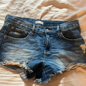 Lågmidjade jeansshorts  - Snygga blå jeansshorts från Ginatricot  med slitna detaljer . Använd fåtal gånger.