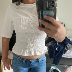Vit smockad topp - Säljer denna vita smockade t-shirt från HM!!💗💗 Endast använd en gång så den är i princip ny❤️ Storlek xxs, men den är stretchig så passar även xs/s🥰