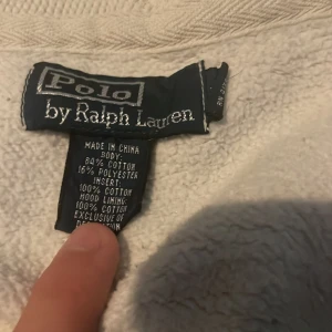 Vit hoodie från Polo Ralph Lauren - Säljer en stilren vit hoodie från Polo Ralph Lauren med dragkedja och broderad logga på bröstet. Tillverkad i en mjuk bomullsblandning för extra komfort. Perfekt för en avslappnad look.