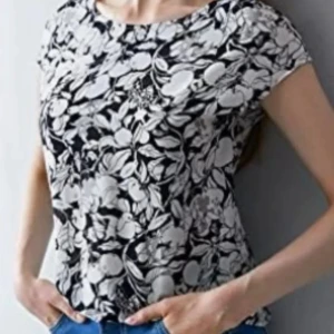 Svartvit blommig topp från MOTF - Säljer en snygg svartvit blommig topp från MOTF i SIDEN. Toppen har korta ärmar och en öppen rygg med knytning. Perfekt för en stilren look med en twist. Materialet är mjukt och bekvämt.