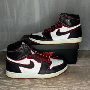 Nike Air Jordans i svart, vitt och rött - Snygga Nike Air Jordans i en klassisk färgkombination av svart, vitt och rött. Skorna har en hög design med snörning och den ikoniska Nike-loggan på sidan. Perfekta för dig som vill ha en stilren och sportig look. Skorna är i väldigt bra skick