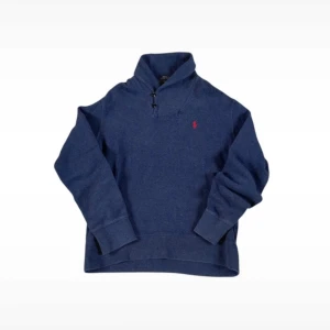 Ralph Lauren hoodie  - Säljer en snygg blå tröja från Ralph Lauren med halv dragkedja och röd broderad logga på bröstet. Perfekt för en stilren look. Tröjan har långa ärmar och är tillverkad i ett mjukt material.
