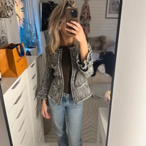 Svartvit jacka/kofta   - Snygg svartvit jacka/kofta från Hallhuber med ett klassiskt rutigt mönster. Långa ärmar och dekorativa knappar framtill. Perfekt för en stilren look!