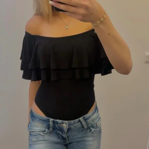 Svart volang body - Jättefin off shoulder body med volang och en tight passform i stretchigt material💗