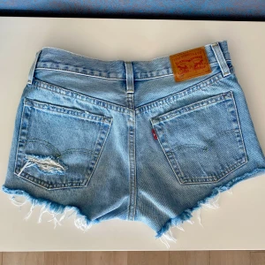 Blå jeansshorts från Levi's - Säljer ett par snygga blå jeansshorts från Levi's med fransiga kanter och slitna detaljer. Shortsen är i toppen skick, säljer då jag har flera jeansshorts 