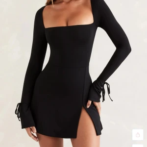 Oh Pollly Svart långärmad klänning med slits - Snygg svart klänning med lång ärm och en stilren slits framtill. Den har en tight passform och knytband vid ärmsluten för extra detalj. Perfekt för en kväll ute! Storlek XS endast använd en gång, helt nytt skick 