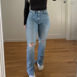 Jeans  - Blåa jeans från Zara med hål på knäna och slits inne vid foten, knappt använda 🩵
