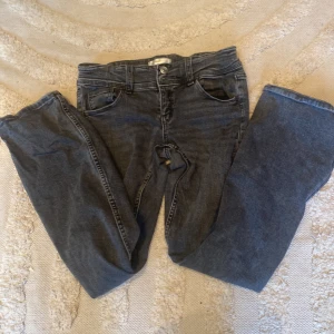 Grå jeans från Gina Tricot - Snygga grå jeans från Gina Tricot med klassisk femficksdesign. De har en knapp och dragkedja framtill samt dekorativa sömmar på bakfickorna. Perfekta för en avslappnad stil.