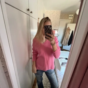 Rosa stickad tröja - Säljer en mysig rosa stickad tröja med v-ringning. Tröjan har långa ärmar och en avslappnad passform, perfekt för kyligare dagar. Passar bra till jeans eller kjol för en avslappnad look.