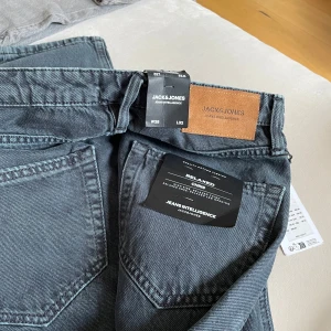 Grå jeans från Jack & Jones helt nya stl 28/32 - Snygga grå jeans från Jack & Jones med en avslappnad passform. " relaxed Chris".  Perfekta för en casual look. Tillverkade i slitstarkt material med klassisk design och knappdetaljer. Superfina i en udda gråblå färg. Stl 28/32