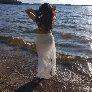 Vit spetskjol - Säljer en vacker vit långkjol i spets. Perfekt för en dag vid stranden eller en somrig utflykt. Kjolen har en elegant och luftig design som ger en romantisk känsla. Passar perfekt för varma dagar och ger en bohemisk touch till din outfit.