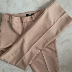 Aprikosfärgade kostymbyxor från Bik Bok - Snygga trendiga aprikos rosa kostymbyxor från BikBok med en klassisk bootcut passform. Byxorna har hällor för bälte. Köpt för ca 499kr