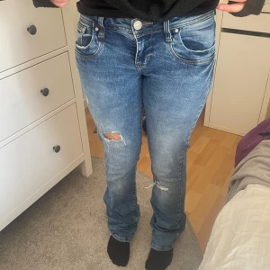 Blå jeans från LTB - Säljer ett par blå jeans från LTB med slitna detaljer och en klassisk femficksdesign. Jeansen har en knappgylf och är i en straight passform. Perfekta för en avslappnad stil.