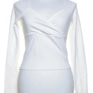 Vit omlottopp från Pamela x NA-KD - Säljer en stilren vit omlottopp från Pamela x NA-KD. Toppen har en elegant v-ringning och långa ärmar, perfekt för en chic look. Denna topp är både bekväm och trendig. Perfekt för att lyfta din garderob! 🤍Storlek M och materialet skulle jag beskriva som tjockt. 