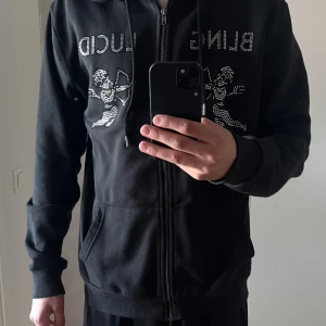 Svart hoodie från Bling Lucid - Snygg svart zip hoodie från Bling Lucid. Tröjan är i riktigt bra skick och är perfekt för en avslappnad look. Nypris: 1000kr. Mitt pris: 400kr. Hör av er vid minsta fråga eller fundering! 