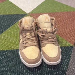 Beige och bruna Nike Air Jordans - Säljer ett par snygga Nike Air Jordans i beige och brunt. Skorna har en klassisk design med snörning och den ikoniska Air Jordan-loggan på plösen. Perfekta för dig som vill ha en stilren look.