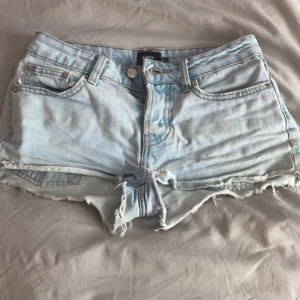 Ljusblå jeansshorts från 157 - Säljer ett par ljusblå jeansshorts från 157 med fransiga kanter och klassisk femficksdesign. Perfekta för sommardagar och festivaler. De har en knappgylf och är tillverkade i slitstarkt denim. Passar perfekt för en avslappnad stil.❤️