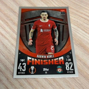 Match Attax fotbollskort Liverpool FC - Säljer ett Match Attax fotbollskort från Topps med en spelare från Liverpool FC. Kortet har en design med lagets emblem och information om spelarens försvars- och anfallsstatistik. Perfekt för samlare av fotbollskort!