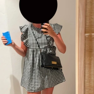 Rutig klänning med volangdetaljer - Säljer en söt rutig klänning med volangdetaljer på axlarna. Supersöt! Använd ett fåtal gånger. Passar mig som bär s. Passar xs och m också!