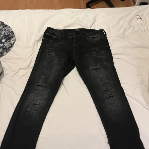 Svarta jeans med slitningar - Snygga svarta jeans med slitningar för en trendig look. De har en klassisk femficksdesign och en bekväm passform. Perfekta för en avslappnad stil. Byxorna är använda ca 5 gonger de är som helt nya och inga defekter✅
