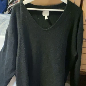 Svart stickad tröja med v-ringning - Mysig svart stickad tröja med v-ringad hals. Perfekt för kyligare dagar och enkel att matcha med olika outfits. Långärmad modell som ger en avslappnad och stilren look.