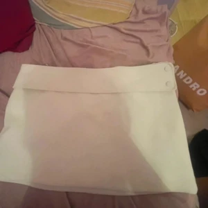 Vit kjol från Zara - Säljer en vit kjol från Zara i storlek L. Kjolen har en stilren design med bred linning och knappar i sidan. Perfekt för dig som gillar minimalistisk stil och vill ha något enkelt classy men snyggt. Mindre än i storleken och ny med prislapp