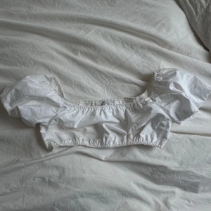 Vit croppad blus med puffärmar från NA-KD - Vit cropped topp från NA-KD. Går att ha både på axlarna samt off shoulder. Endast använd en gång. I storlek 34