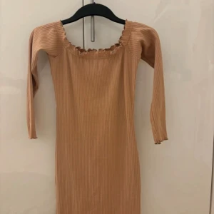 Beige ribbad klänning från Missguided - Säljer en beige ribbad klänning från Missguided Petite. Of shoulder,volangkant och är figurnära. 