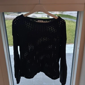 Svart stickad tröja från Bubbleroom - Säljer en svart stickad tröja från Bubbleroom i storlek S. Tröjan har ett genomgående hålmönster och långa ärmar. Perfekt att styla med ett linne under för en cool look.