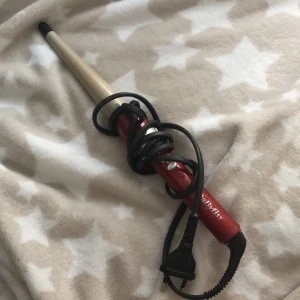 Röd konformad locktång från BaByliss - Konformad locktång i rött och guld från BaByliss. Perfekt för att skapa naturliga lockar och vågor. Har svart spets och sladd med EU-kontakt. Enkel att använda för olika frisyrer.